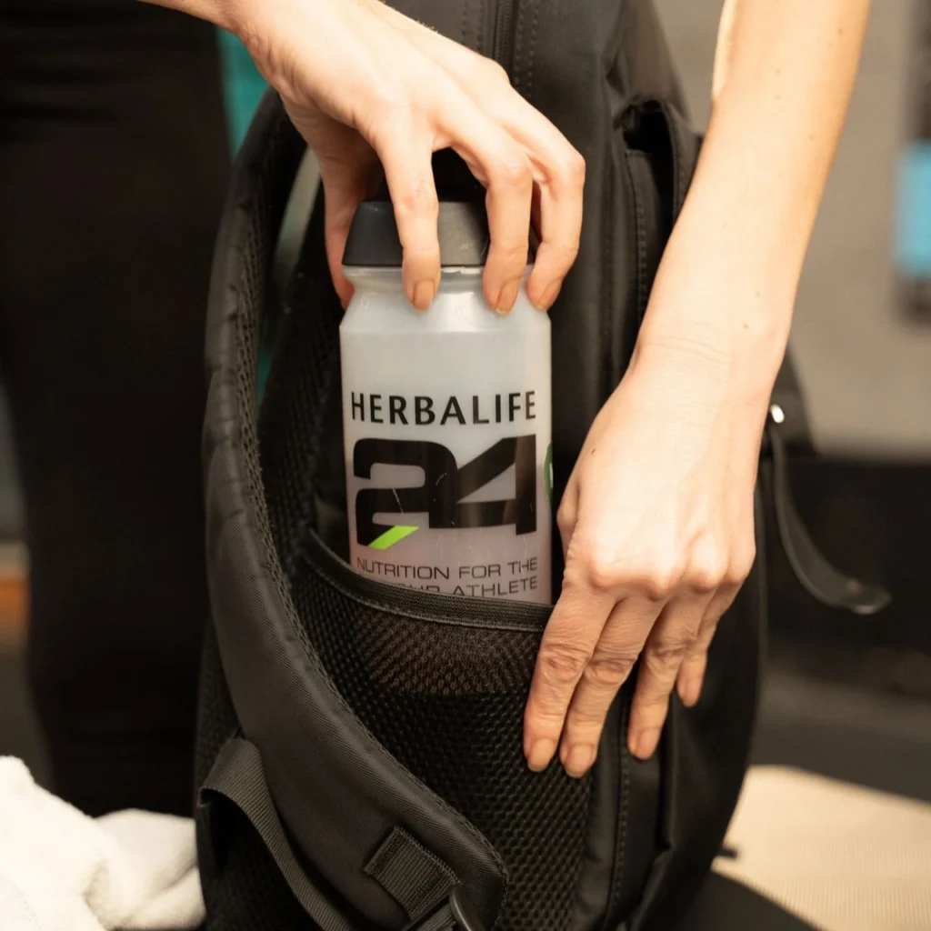 Herbalife24 Shaker wird in die Seitentasche eines schwarzen Sportrucksacks gesteckt