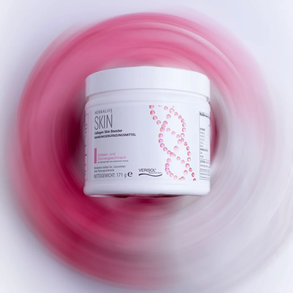 Herbalife SKIN Collagen Skin Booster Erdbeer- und Zitronengeschmack in der 171g Dose vor einem rosa-weißen Hintergrund.