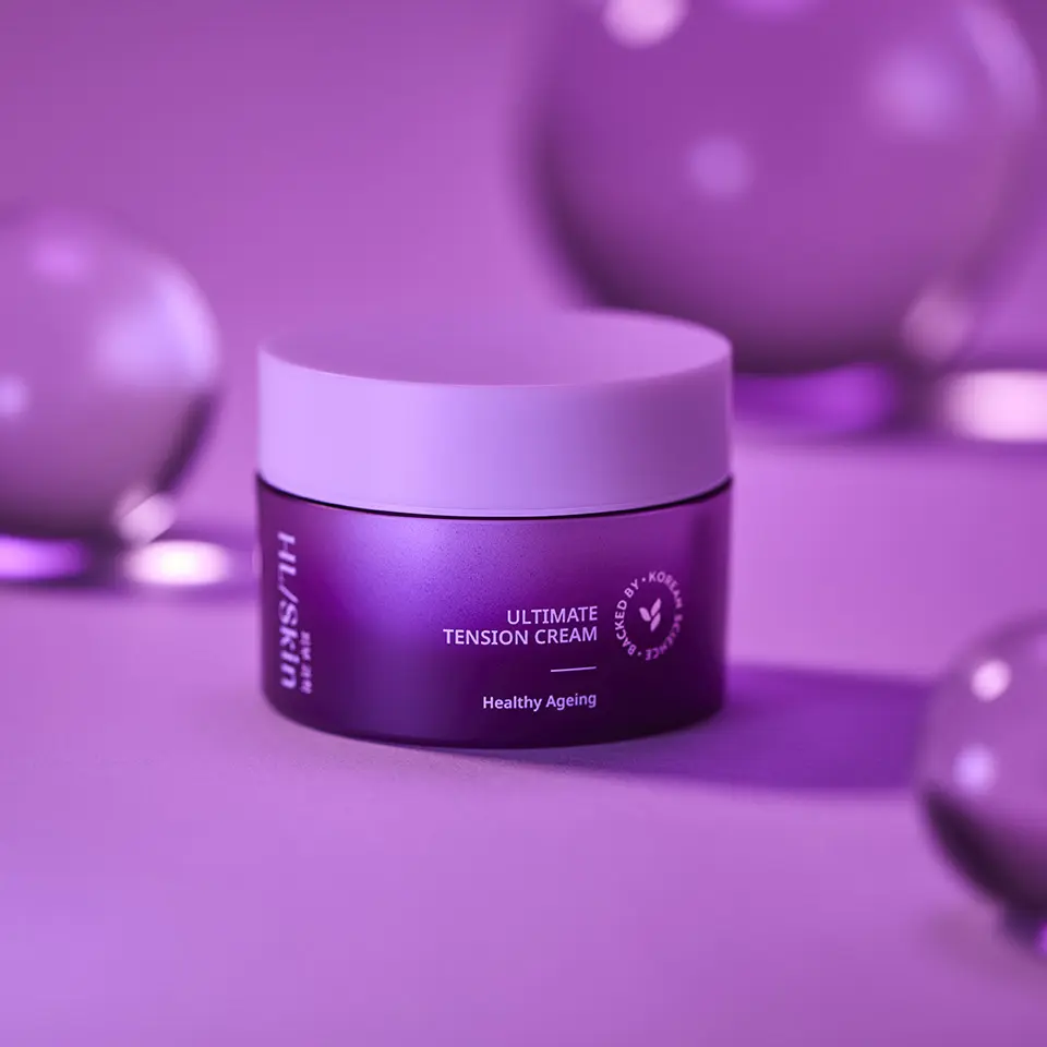HL/Skin Ultimate Tension Cream in violetter Produktinszenierung mit dekorativen Kugeln im Hintergrund